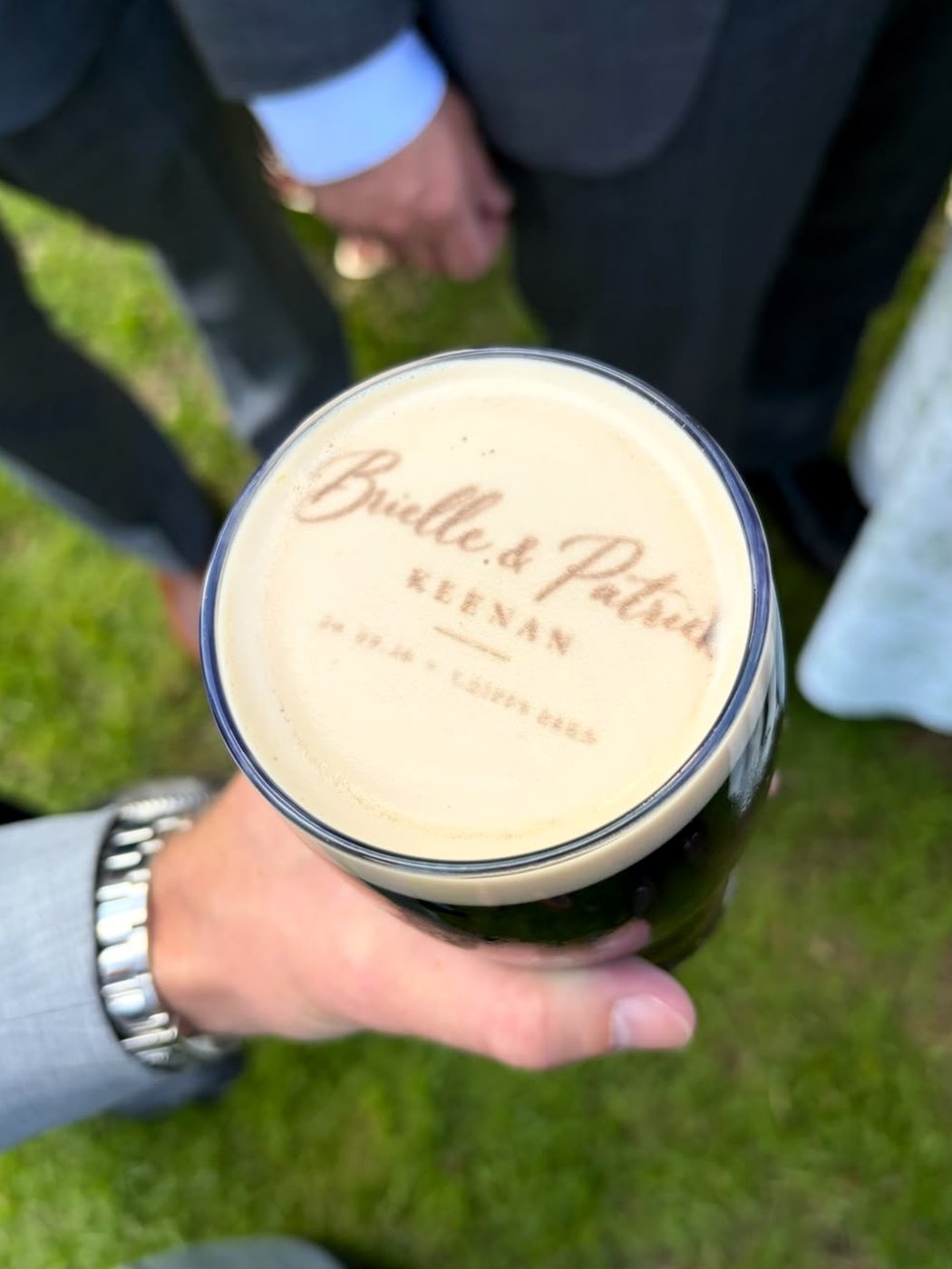 Guest holding a pint of Guinness with the bride and groom's names printed on the foam at a Cotswolds wedding