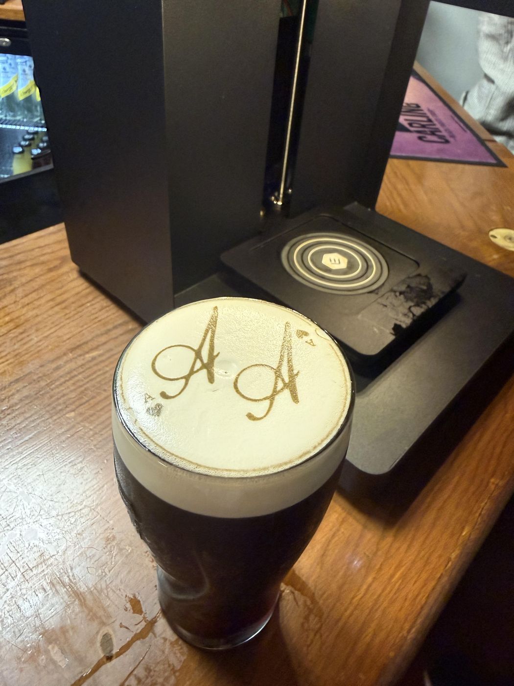 Wedding monogram printed on the foam head of a Guinness pint next to the pint printer machine